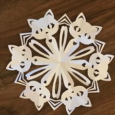 an origami snowflake made out of white paper on a wooden table