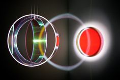 two circular lights hanging from the ceiling in front of a black wall with red and green circles