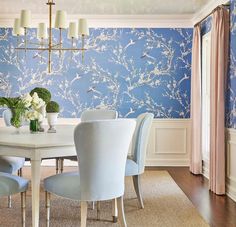 a dining room with blue wallpaper and white chairs