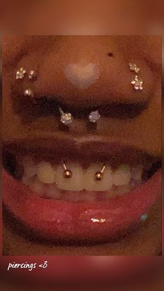 a close up of a person's mouth with gold piercings on their teeth