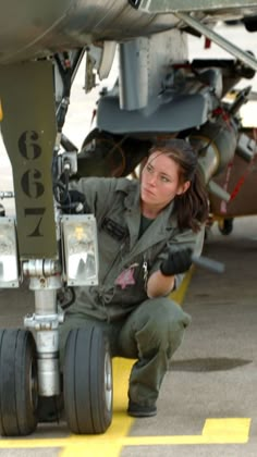 a woman kneeling down next to an airplane