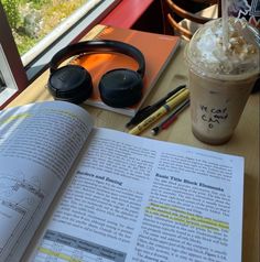 an open book sitting on top of a table next to a cup of coffee