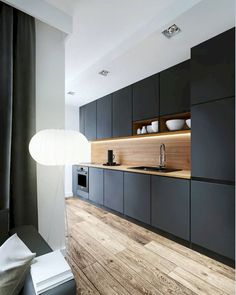 a modern kitchen with black cabinets and wood flooring is pictured in this image from the front view