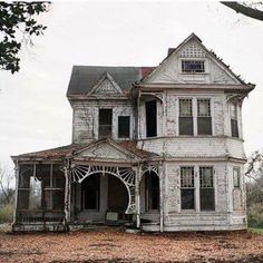 an old, run down house sits in the middle of a leaf covered field with trees