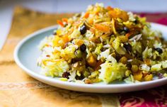 a white plate topped with rice covered in raisins and other toppings on top of a colorful table cloth