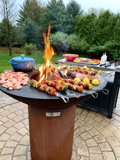 a fire pit with food on it and grills in the backgroung