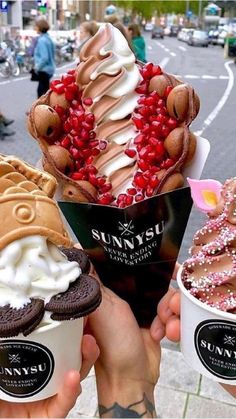 three ice cream sundaes with toppings in their hands on the street corner