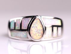 // Solid Sterling Silver White Fire Opal Inlay Ring // This high-quality ring is made with white fire opal, which is a man-made gemstone. The gemstones are carefully inlaid together to create this beautiful geometric design!  The ring measures 9mm at the widest point. Each ring contains fire opals that create an iridescent effect that can't be quite captured in a photo! The opal colors shimmer, depending on the lighting and angle. Thanks for looking! Modern White Opal Ring For Gift, Modern White Opal Gemstone Ring, Modern White Opal Ring, White Teardrop Opal Ring For Gift, Opal Inlay Ring Gift, Opal Ring With Inlay Perfect For Gifts, Gift Opal Inlay Ring, Fire Opals, Inlay Jewelry