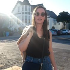 a woman is standing on the sidewalk with her hand in her pocket