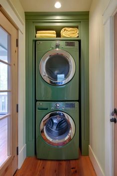 a green washer and dryer in a room with wood flooring next to an open door