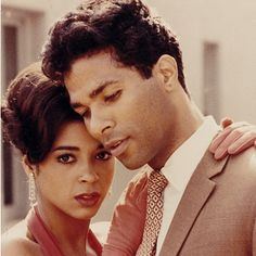 a man in a suit and tie standing next to a woman with her eyes closed