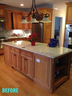 a large kitchen with wooden cabinets and an island in the middle is lit by two pendant lights