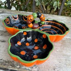 two orange and black bowls sitting on top of a wooden table