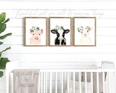 three framed cows with flowers on their heads are hanging in a white crib next to a green plant