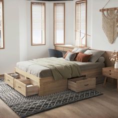 a bed with two drawers underneath it in a room next to wooden furniture and windows