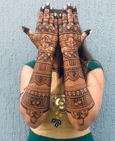 a woman holding her hands up to her face with hendi tattoos on it's arms