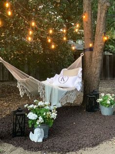 a hammock is set up in the yard with potted plants and lights