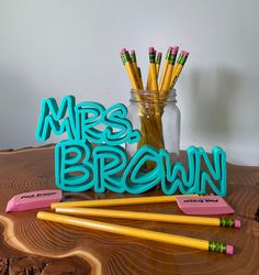 some pencils and markers are sitting on a wooden table next to a jar with the word mrs brown