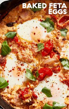 baked feta eggs with tomatoes and basil in a cast iron skillet on a white background