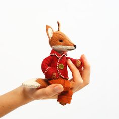 a person holding a small stuffed animal in their hand