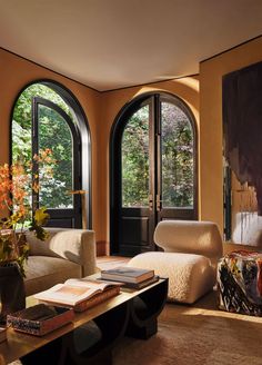 a living room filled with lots of windows and furniture next to a painting on the wall