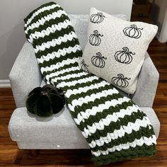 a green and white striped blanket sitting on top of a couch next to a pillow