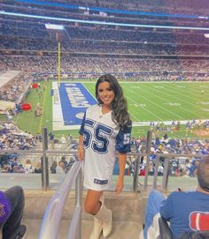 a woman in a football uniform standing on the bleachers at a sporting event