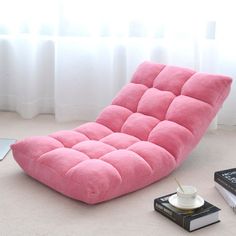 a pink futon chair sitting on top of a white floor next to a book