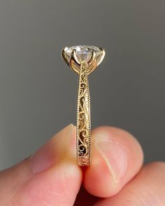 a close up of a person's hand holding a ring with a diamond in it