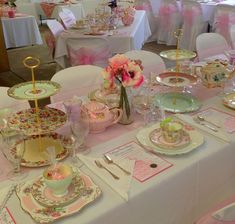 a table set up for a tea party with pink and white decorations on it,