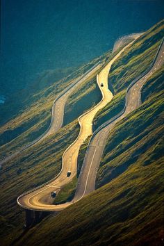 an aerial view of two winding roads on the side of a hill with cars driving down it