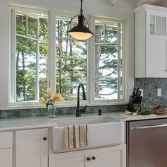 a kitchen with white cabinets and stainless steel dishwasher, sink, and window