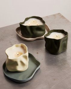 three candles sitting on plates with one candle in the middle