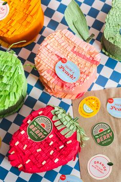 paper strawberries are sitting on a checkered tablecloth with stickers attached to them