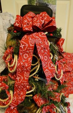 a christmas wreath with red and white bows on it sitting on top of a chair