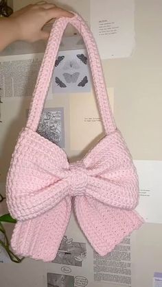 a pink knitted purse with a large bow hanging from it's front loop