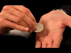 a man holding a coin in his hands with another person's hand on the other side