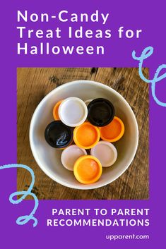 a white bowl filled with orange and black plastic candy candies on top of a wooden table