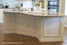 a large kitchen with white cabinets and marble counter tops, an island in the middle