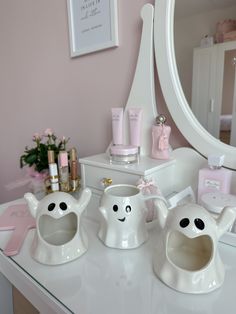 a white vanity with three teapots on it and a mirror in the background