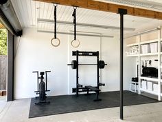 a home gym with white walls and black flooring