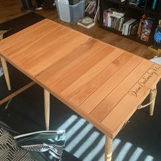 a wooden table with writing on it in front of a bookshelf full of books