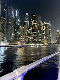 the city skyline is lit up at night as seen from a boat in the water