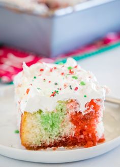 a slice of cake with white frosting and sprinkles on a plate