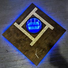 a star wars clock is shown on a wooden surface with blue light coming from it