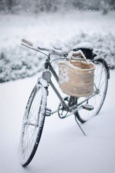 a bicycle is covered in snow and has a basket on the handlebars,