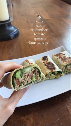 a person is holding a burrito on a plate