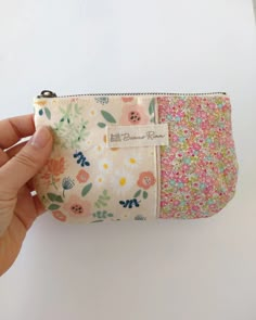 a hand is holding a small pouch with flowers on it