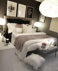 a white bed sitting in a bedroom next to two lamps and pictures on the wall