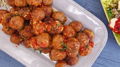 meatballs with sauce and herbs on a white plate